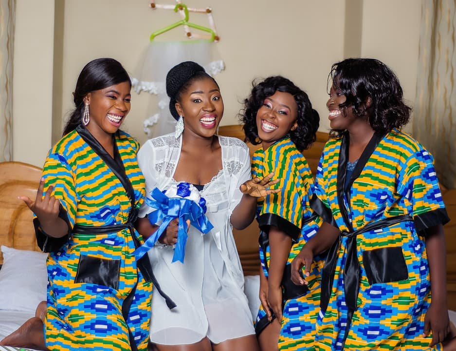 Bridal party posing joyfully in colorful robes.