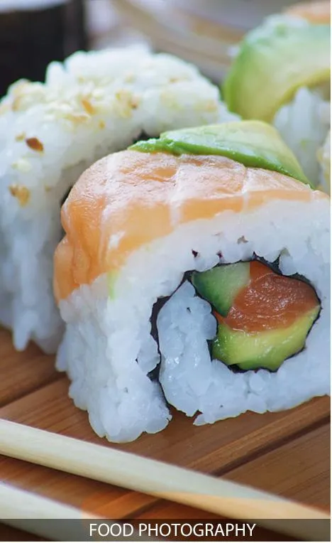 Close-up of sushi rolls with rice, salmon, and avocado.