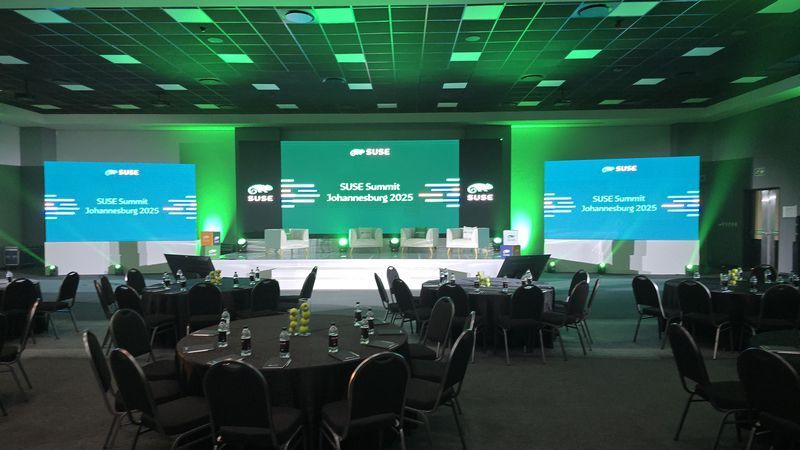 Event setup featuring uplighting and screens for SUSE Summit 2025.