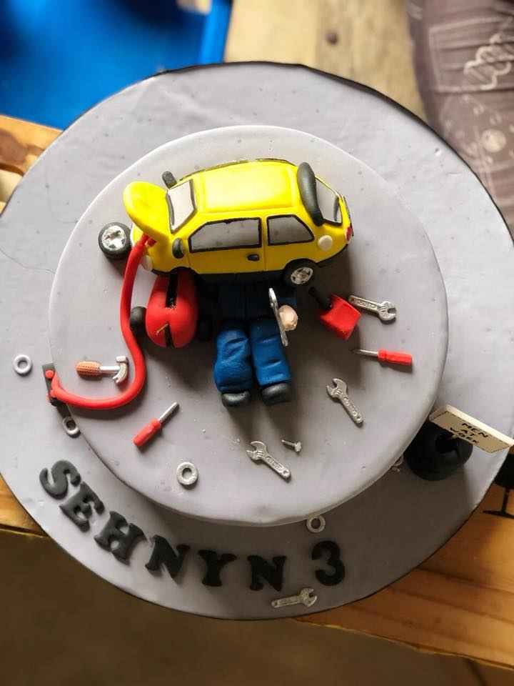 A birthday cake decorated with a car and mechanic tools