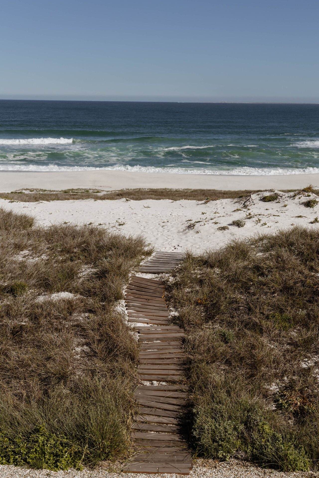 Wooden pathway through grass leading to the beach