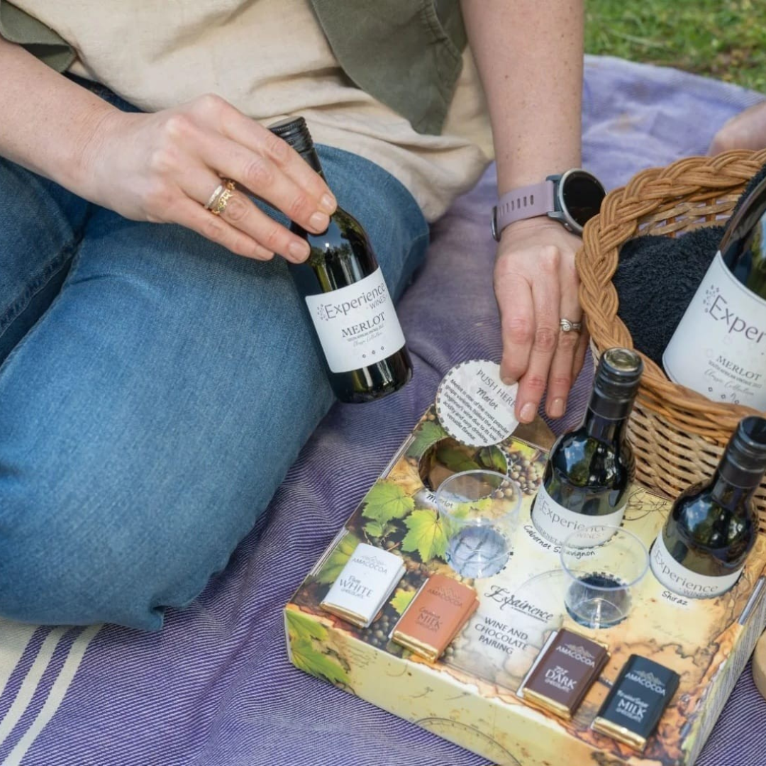 Hand holding a wine bottle with chocolates arranged in a tasting set