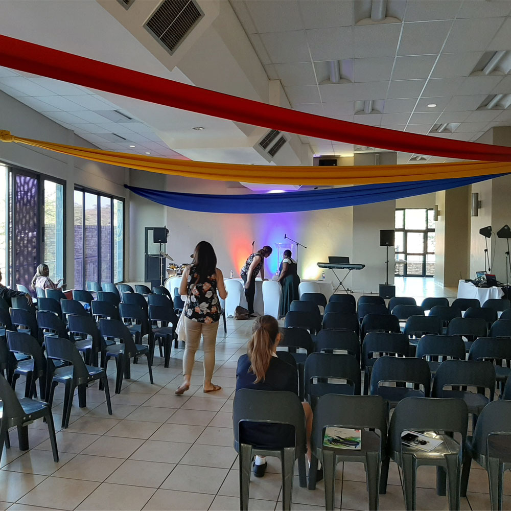 A brightly lit venue with colorful draping and seating arrangement.