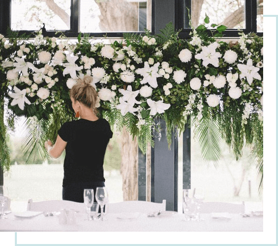 Flower arrangement with white lilies and greenery above a dining table