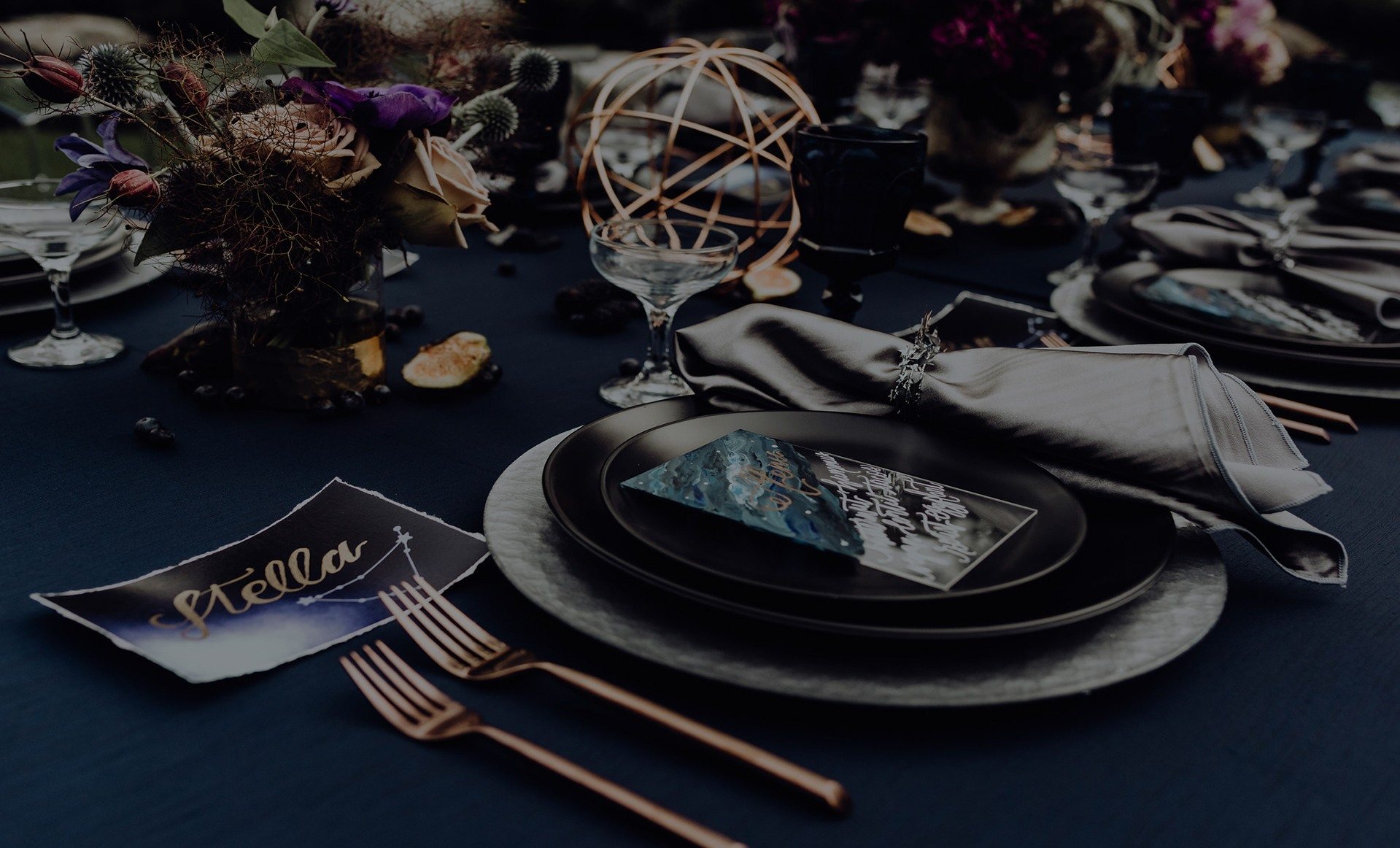 Elegant table setting with dark blue cloth and floral centerpieces.