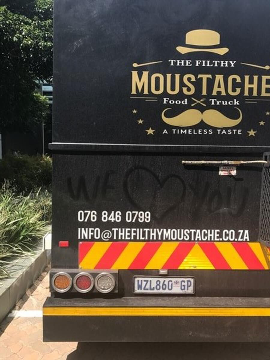 Back of The Filthy Moustache food truck with logo and message