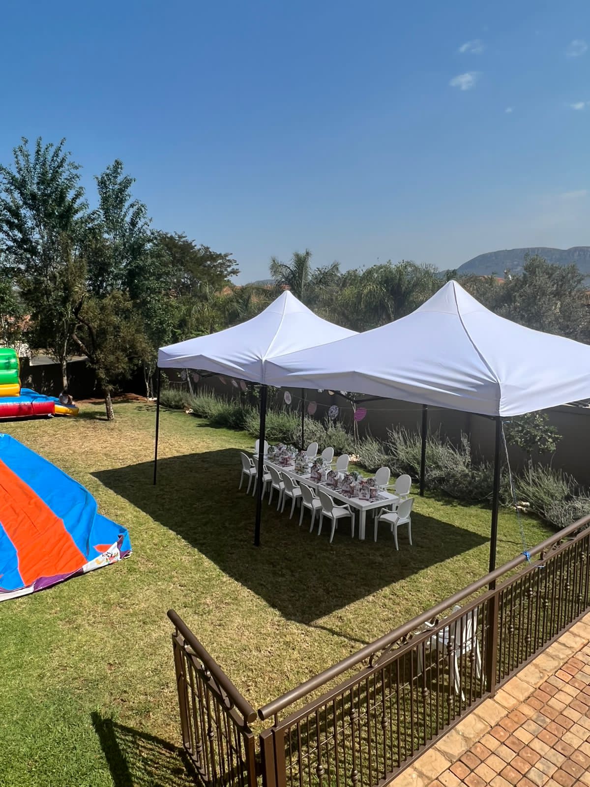 Two white outdoor gazebos set up for an event in a garden