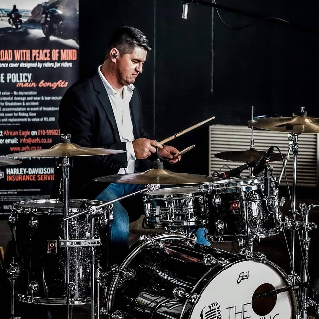 Drummer performing at an event with drums set up.