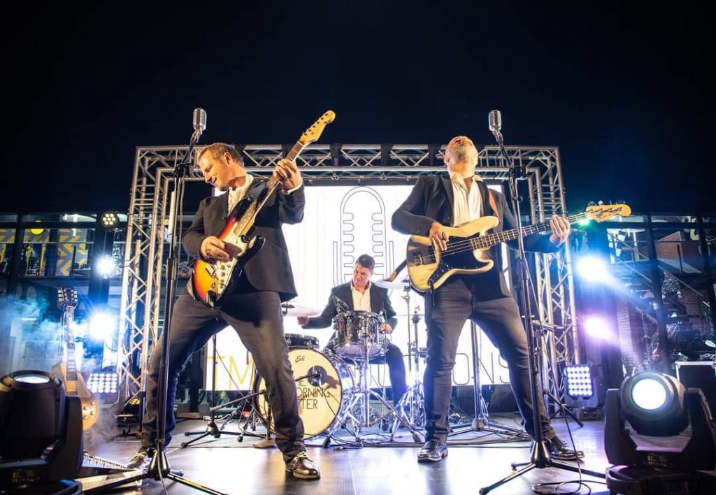 Three musicians performing live with instruments on stage