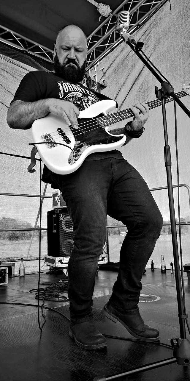 Musician on stage playing white bass guitar.