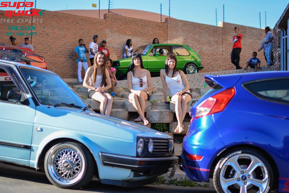 Car show scene with people sitting near colorful vehicles.
