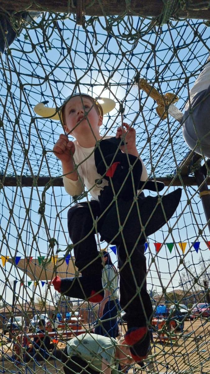 Child climbing on netting in adventure play area