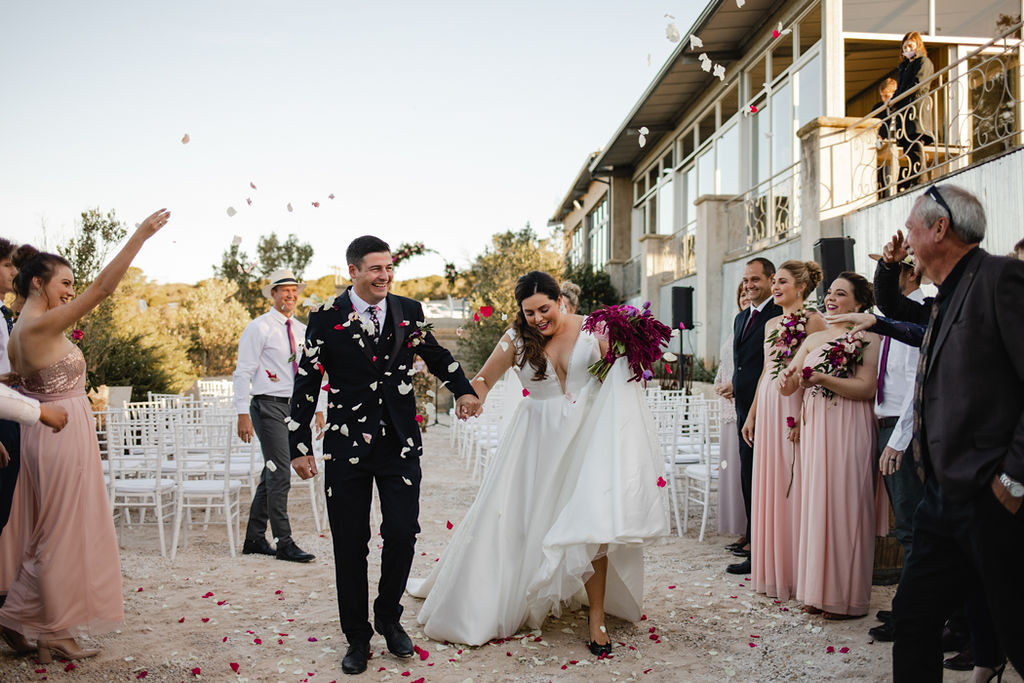Newlyweds leaving ceremony with flower petals