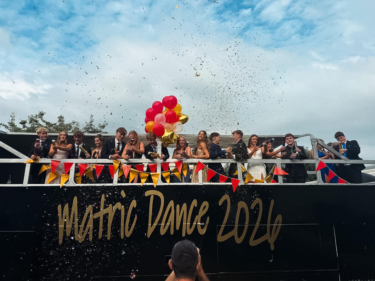 Group of students celebrating matric dance on a party bus with decorations.