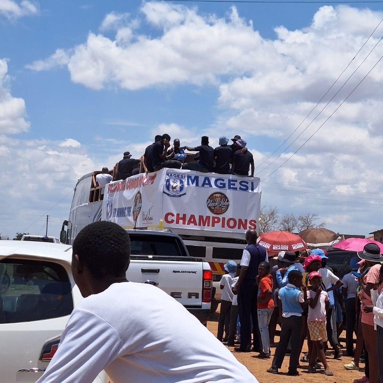 Party bus with celebratory banner and people onboard during a parade