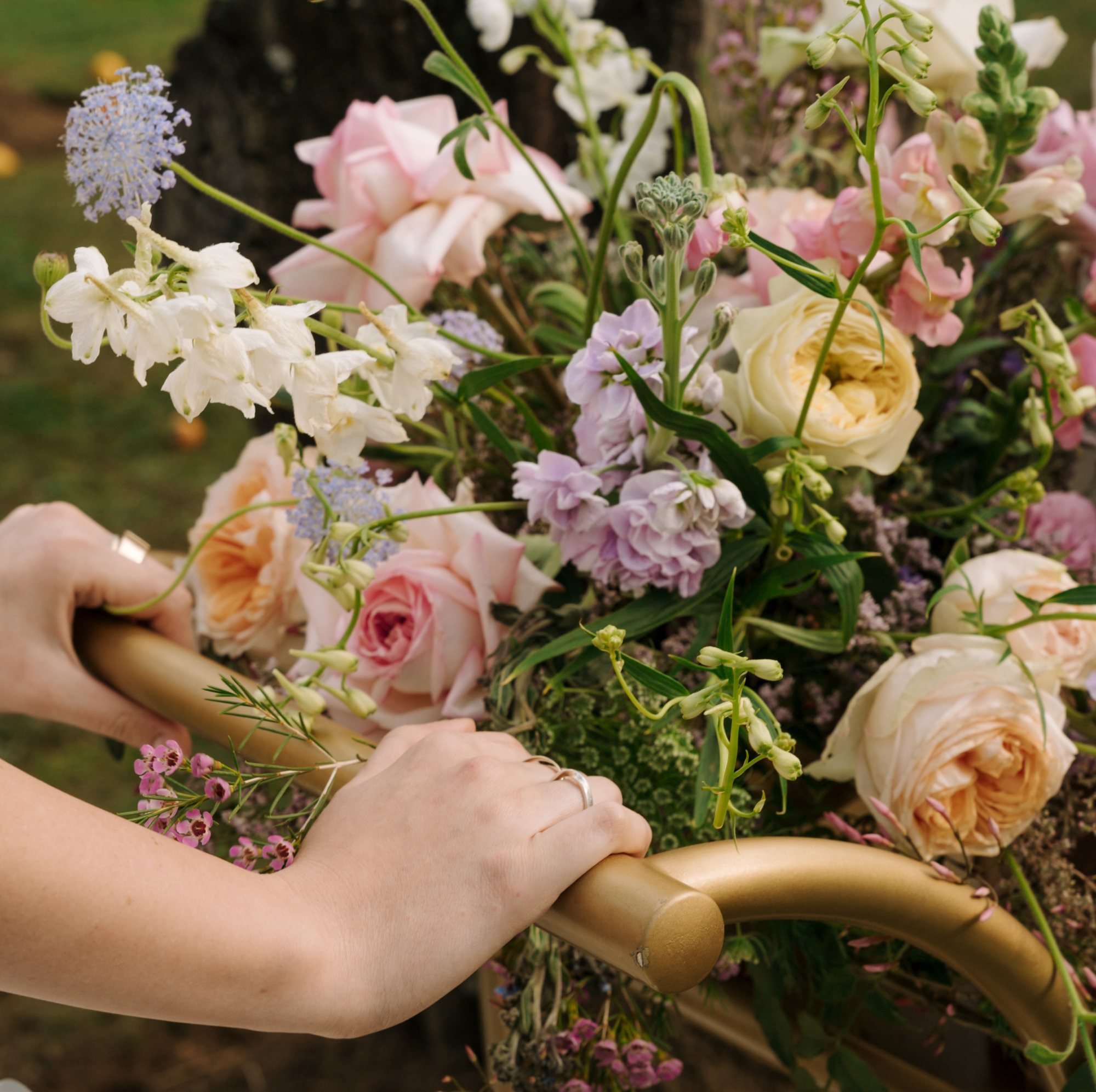 Hands holding a cart with a variety of floral arrangements