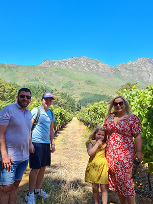 Family posing in vineyard with mountains in background