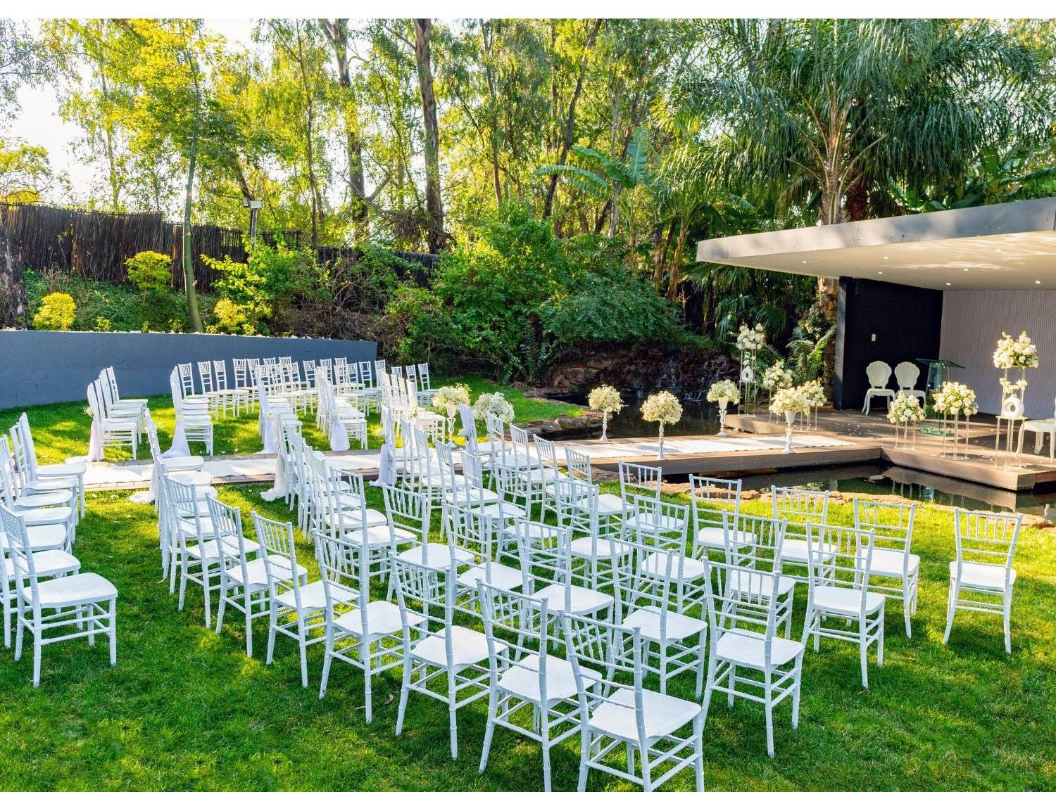 Outdoor wedding ceremony setup with white chairs and floral decor