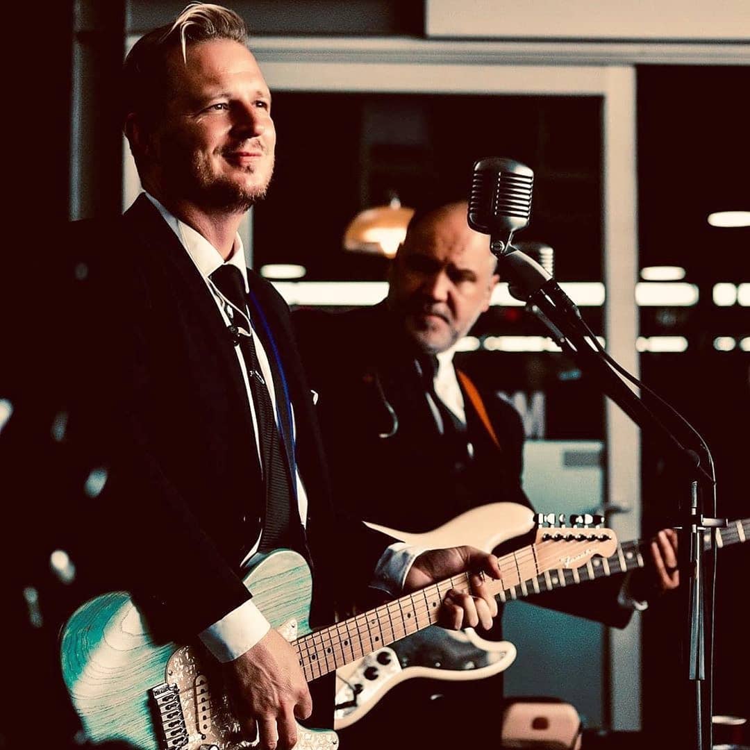 Two musicians performing with guitars and a microphone