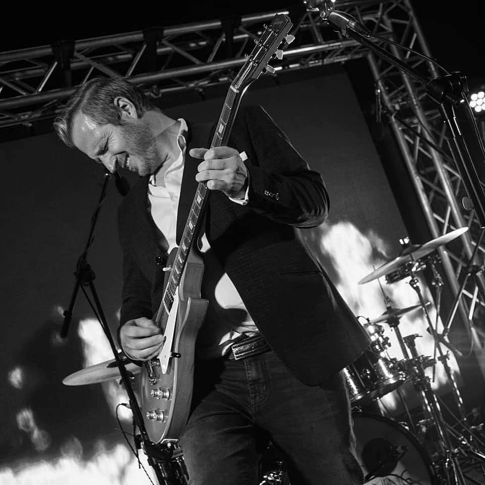 Guitarist performing live with a dramatic backdrop.