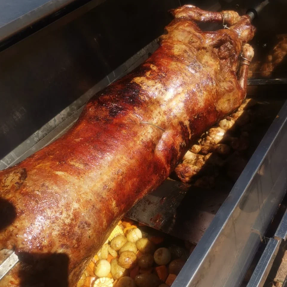 Whole lamb roasting on a spit with potatoes
