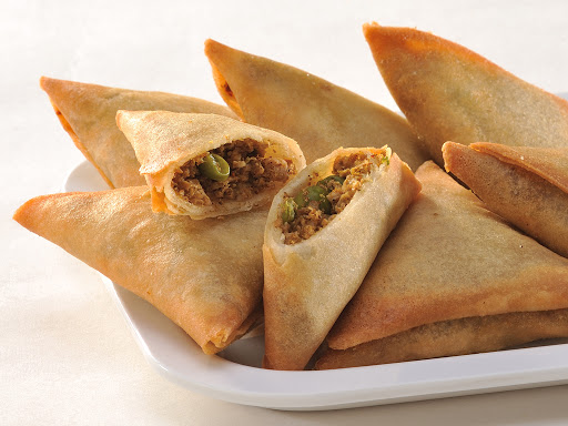 Plate of vegan samosas, some cut open to show filling