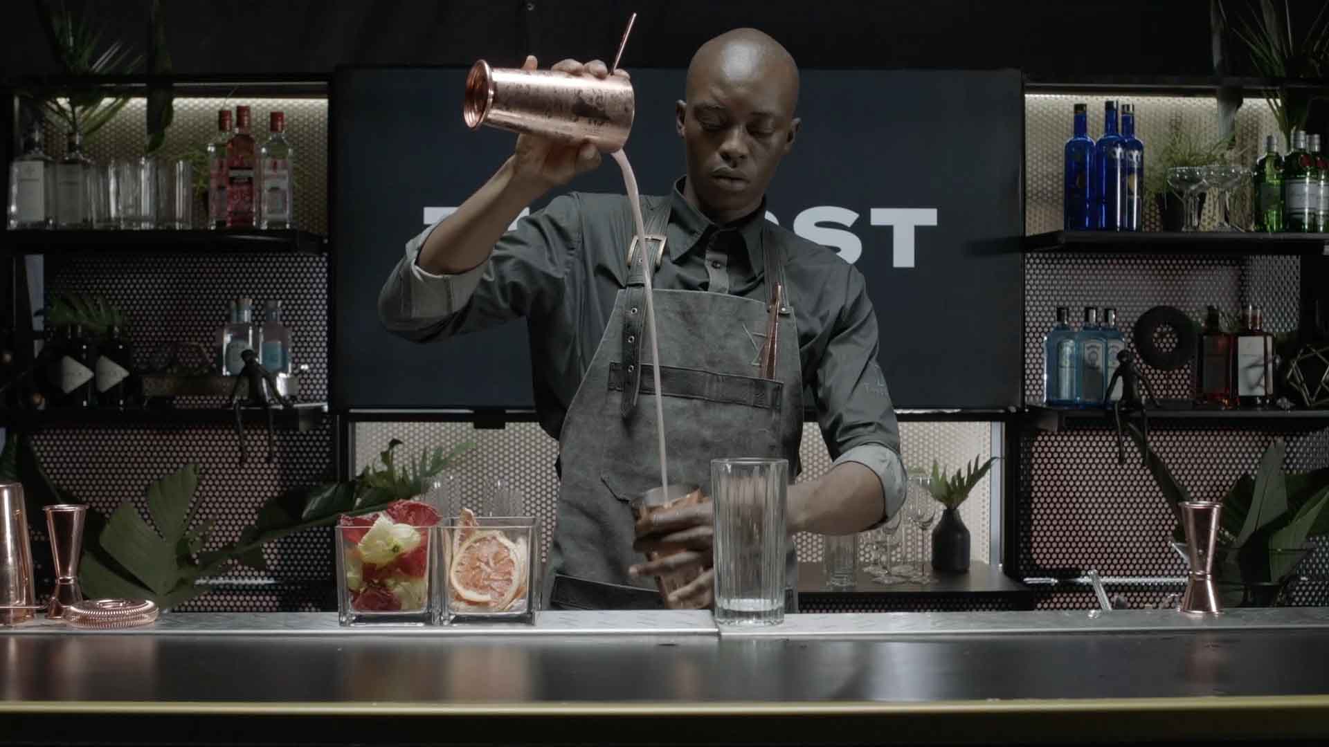 Bartender pouring cocktail from shaker at a bar