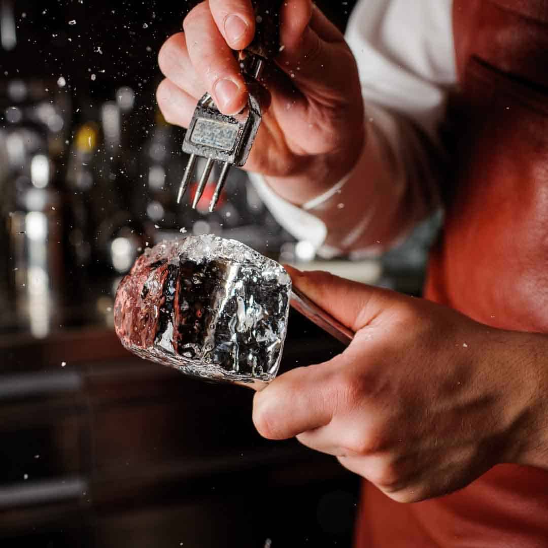 Bartender carving a large block of ice for cocktails
