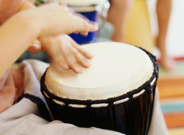 Hands playing a drum during a children's drumming session
