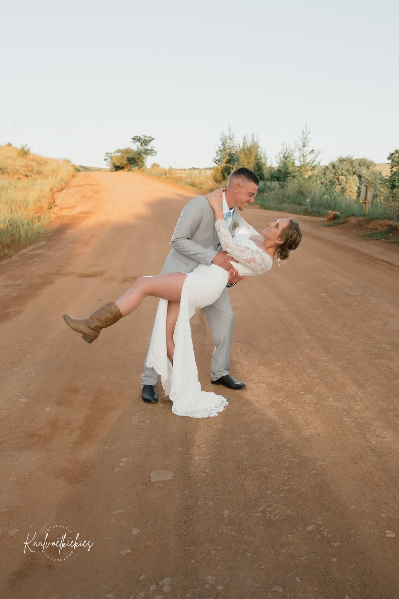 Bride and groom posed on a dirt road