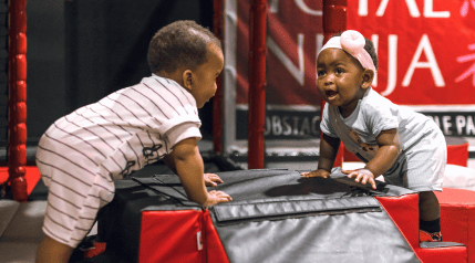 Two toddlers playing on an inflatable obstacle at Total Ninja