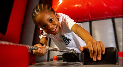 Child smiling while climbing on an inflatable obstacle course