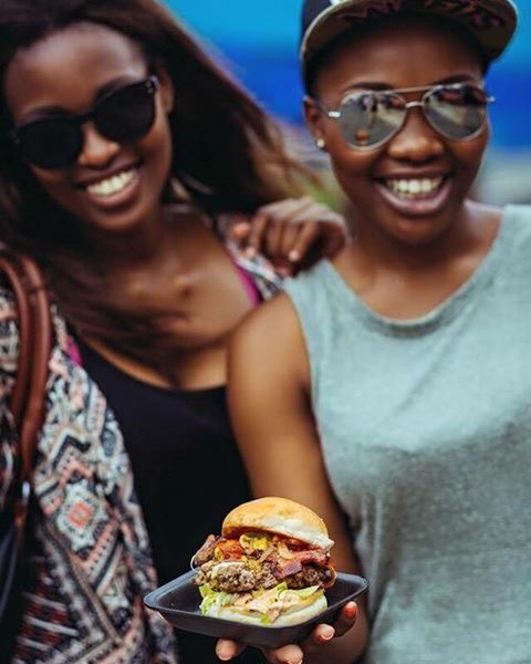 Two women smiling, one holding a gourmet burger