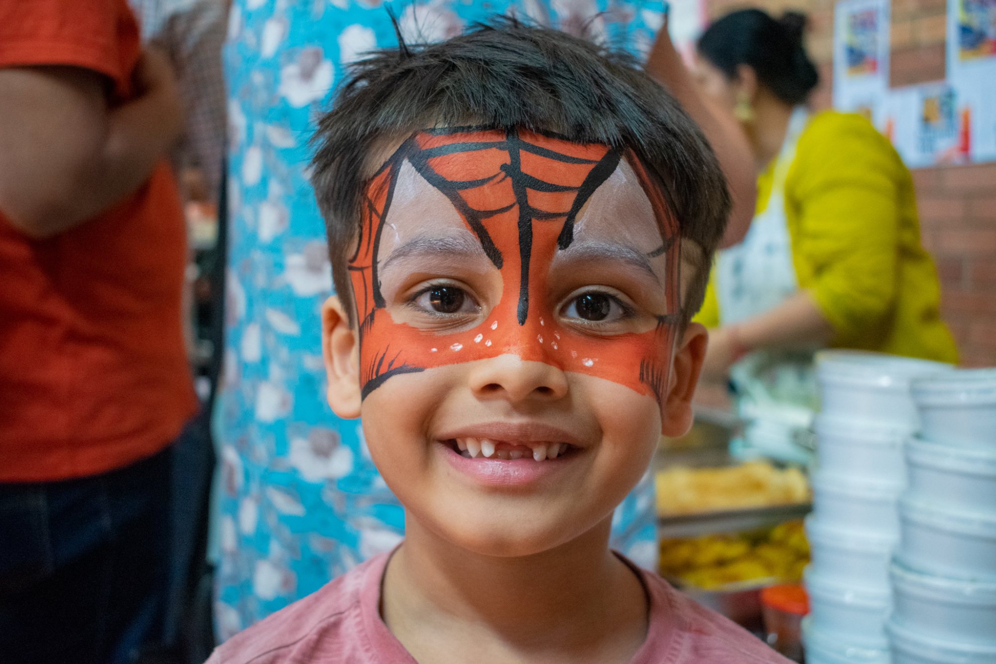 Child with Spider-Man face paint smiling at an event