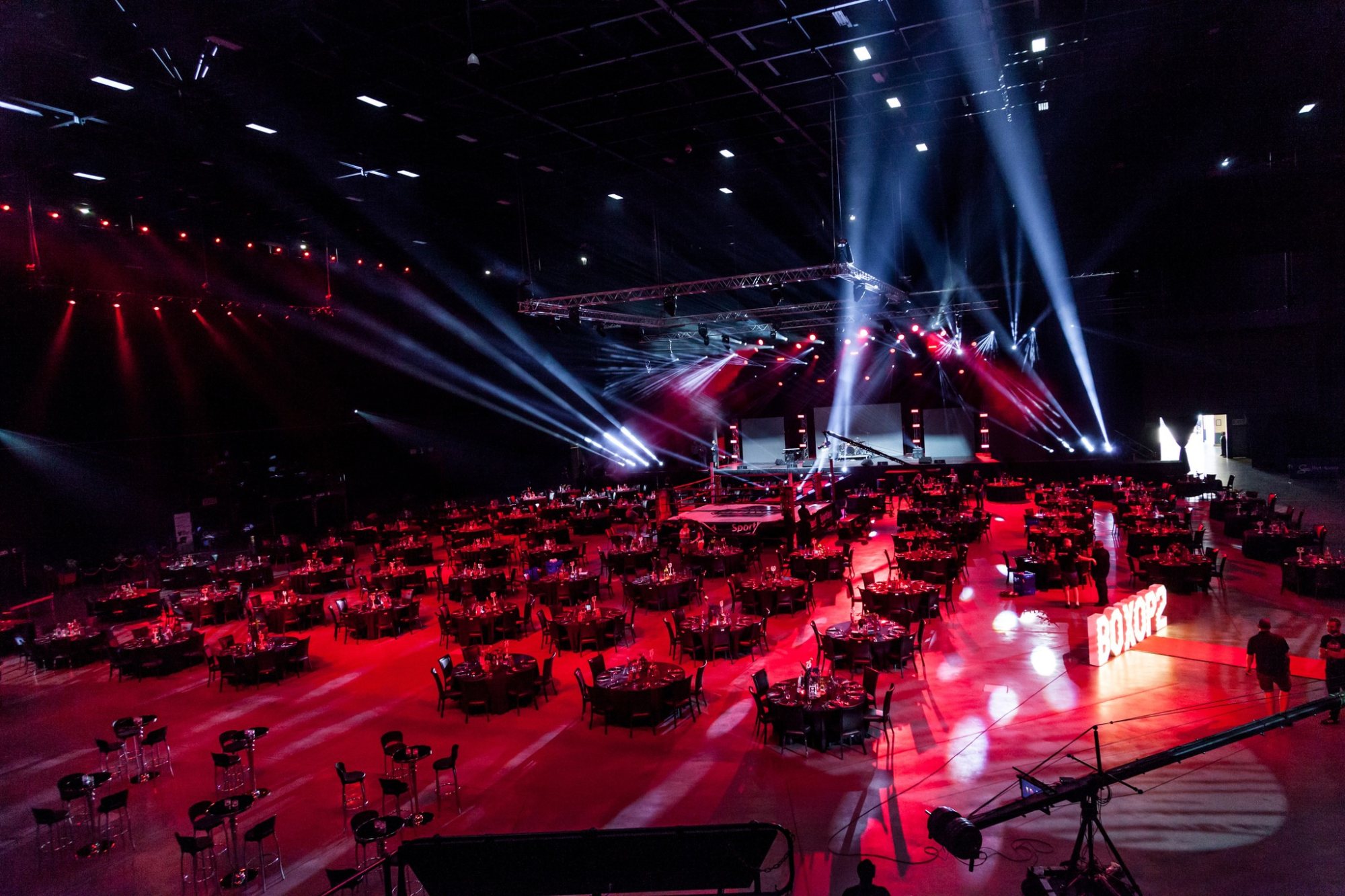 Event hall with red lighting and set tables for dining