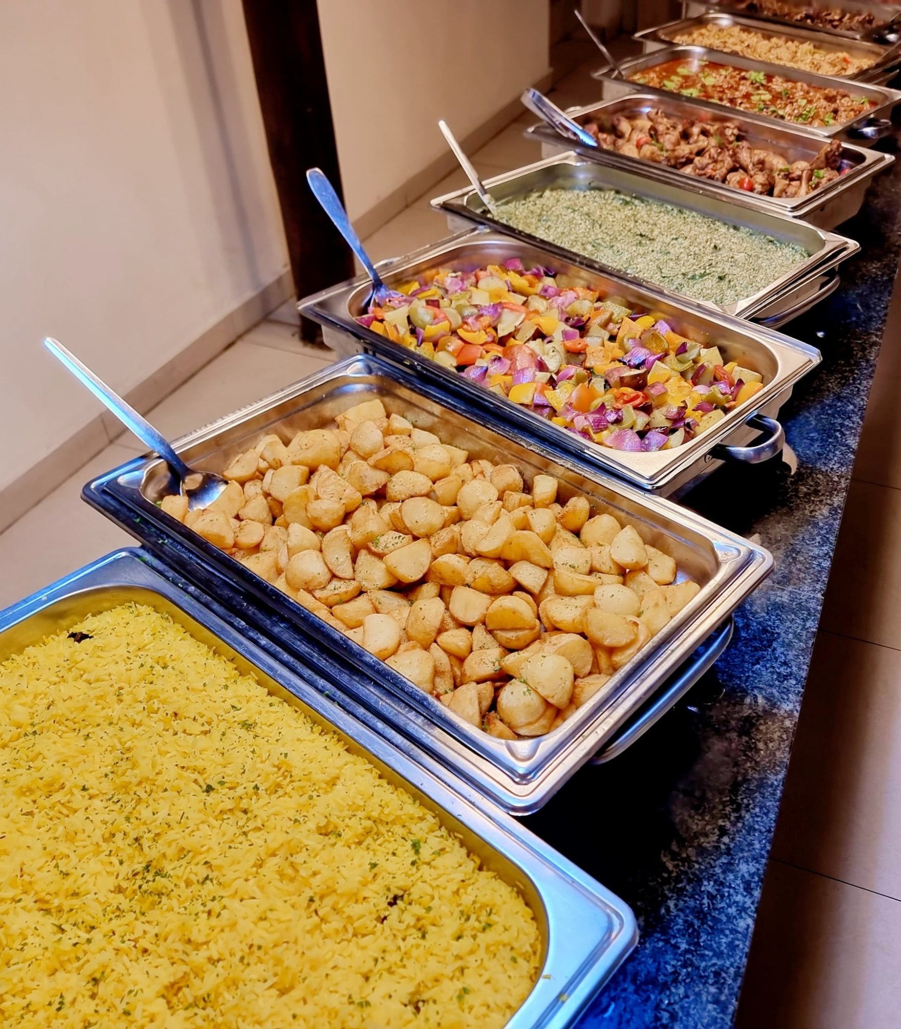Buffet trays with rice, potatoes, and vegetables