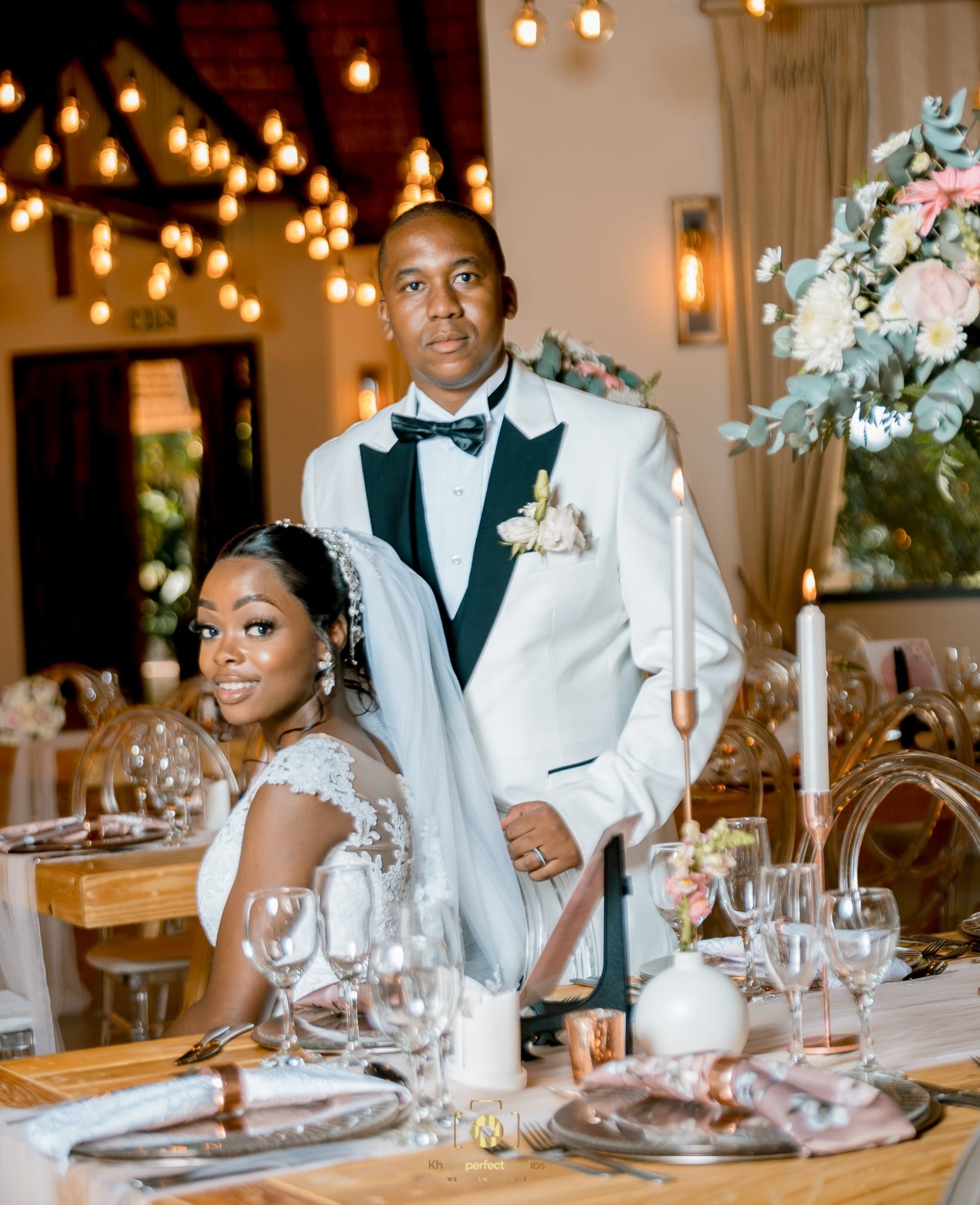 Newlyweds at an elegantly set wedding reception table
