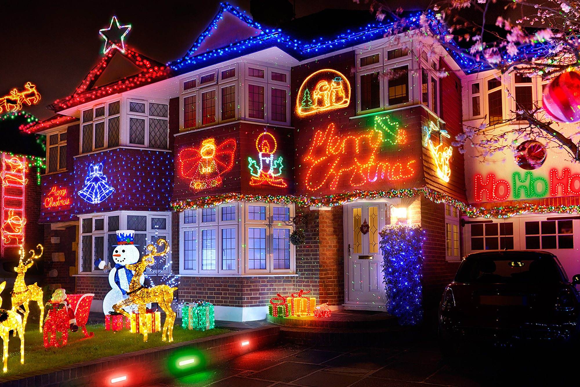 A house decorated with colorful festive lights and holiday motifs.