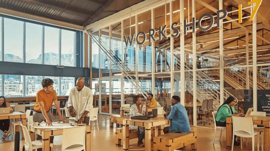 Open workspace with wooden tables and natural light highlighting people engaged in discussions.