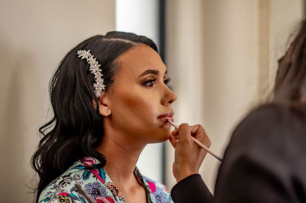Bride receiving lip makeup application with floral robe.