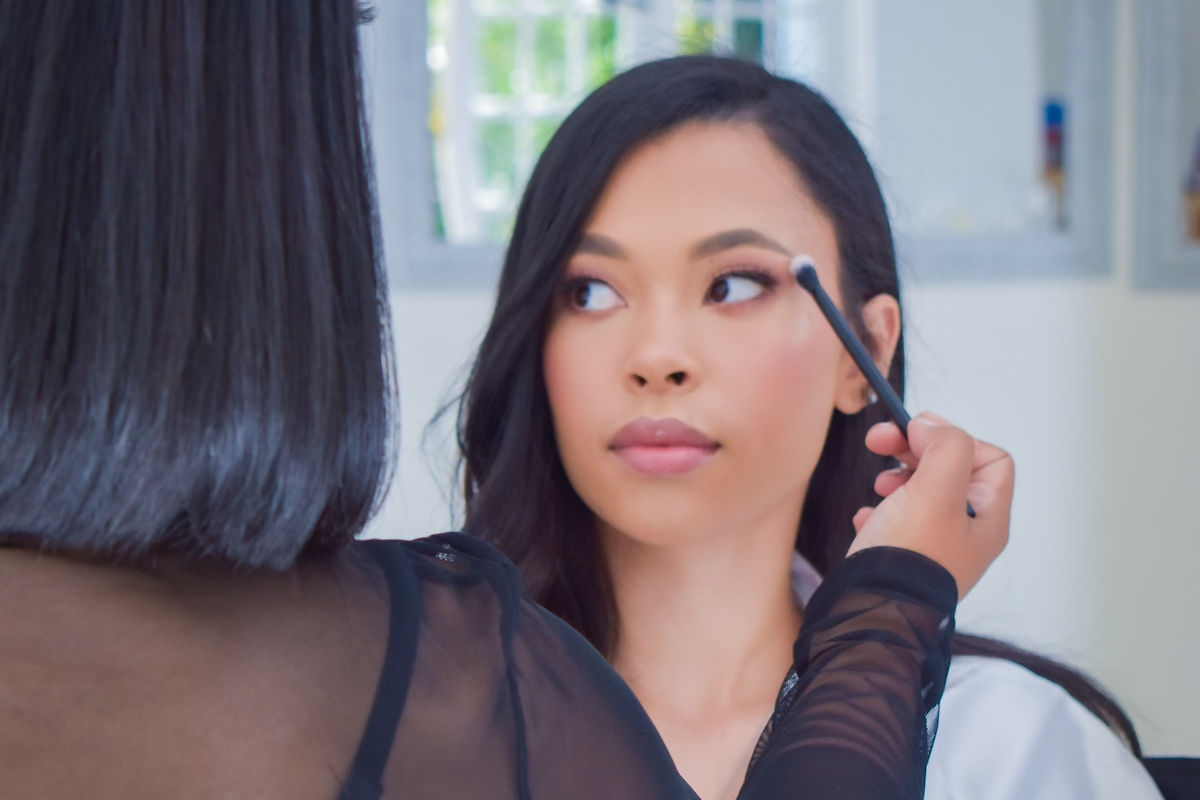 Makeup artist applying eyeshadow to a bride.