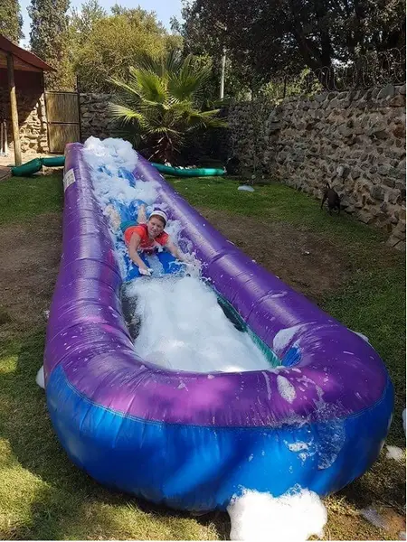 Child sliding down a purple inflatable water slide