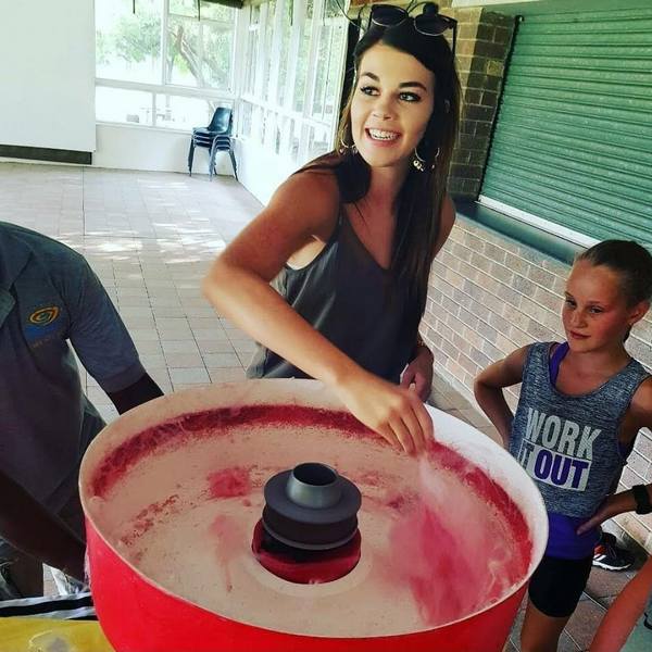 Woman operating a cotton candy machine with a girl watching.