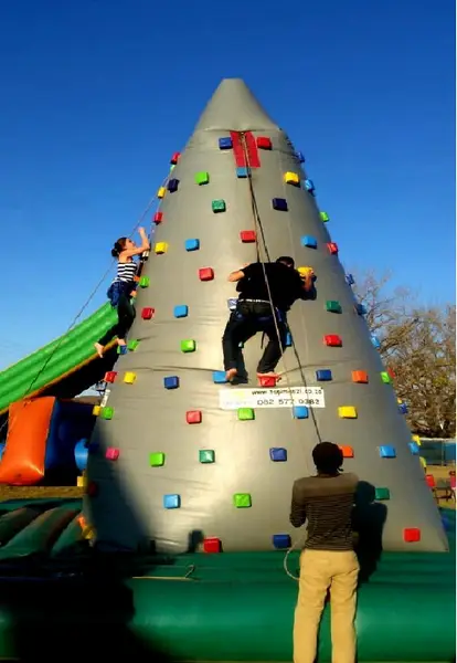 Two people climbing a colorful inflatable climbing wall.