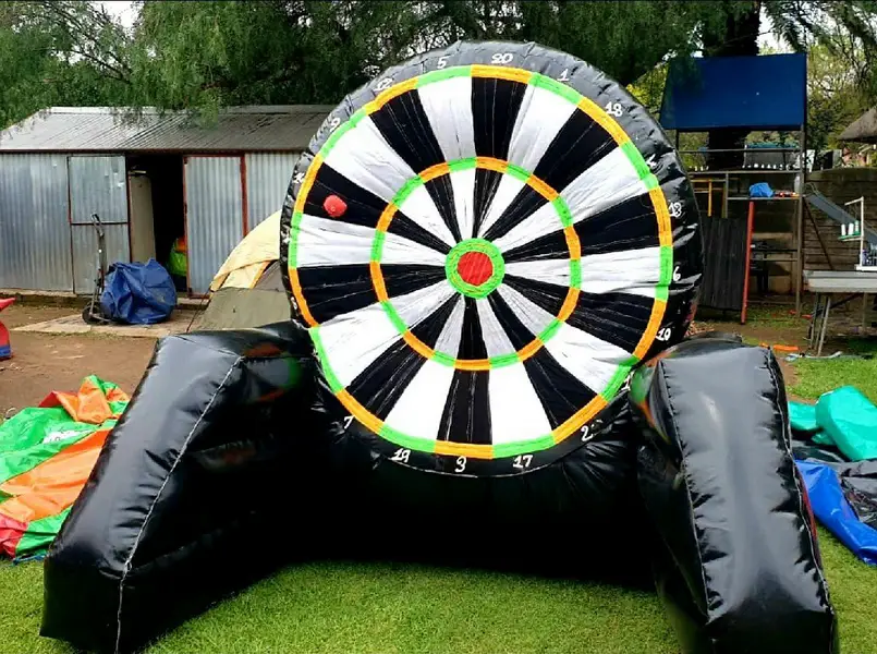 Inflatable dartboard setup on grass with colorful tarps