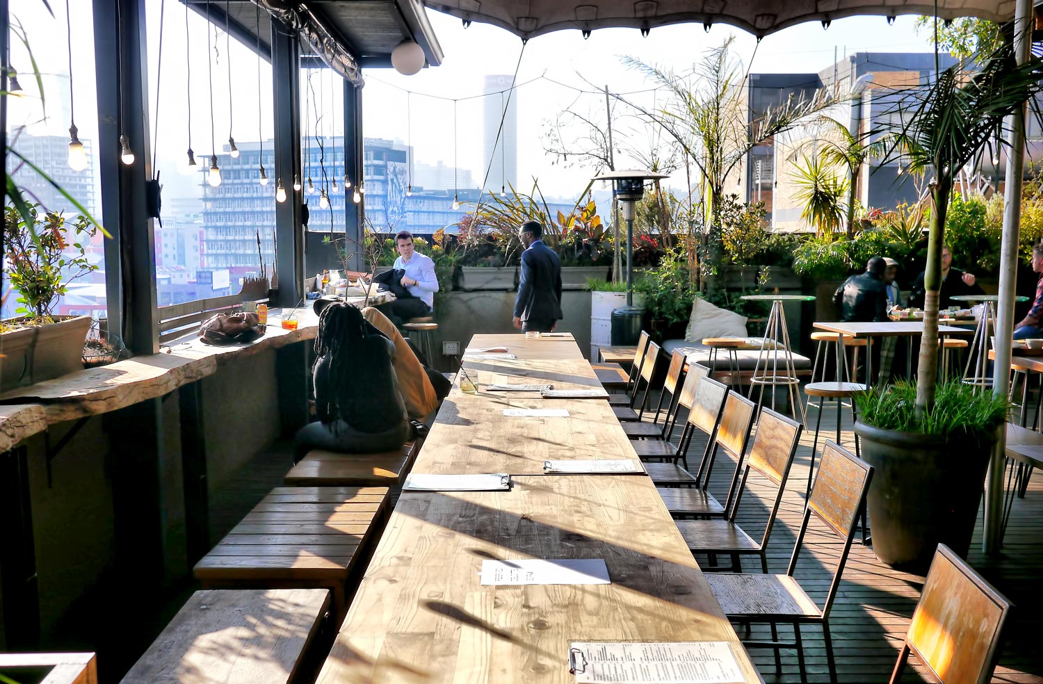 Rooftop dining area with wooden tables and plants