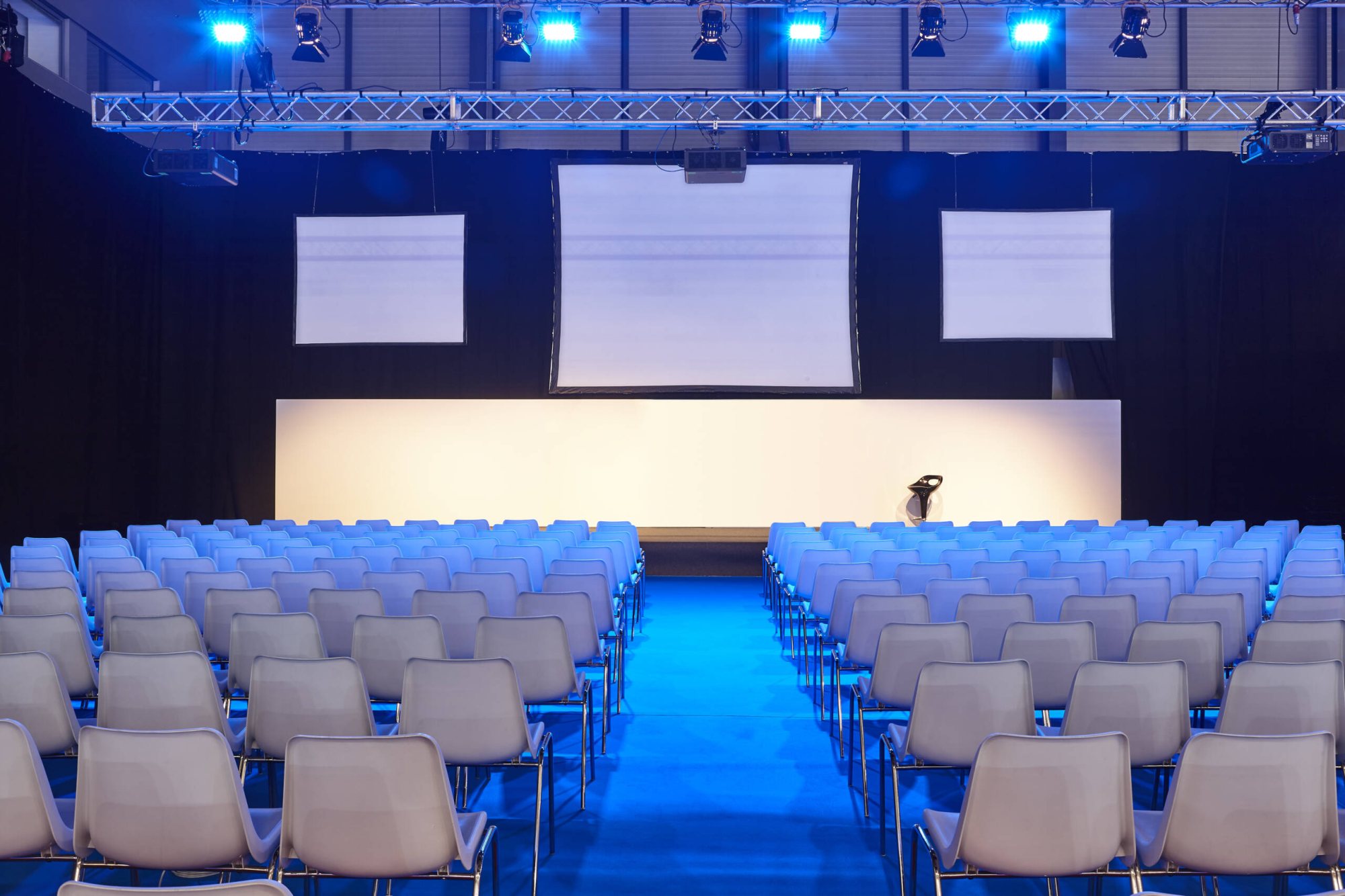 Corporate event venue with rows of chairs and projection screens