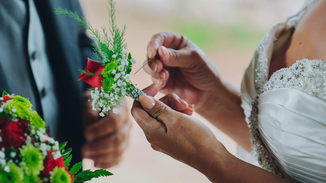 Hands attaching a boutonnière on a wedding day