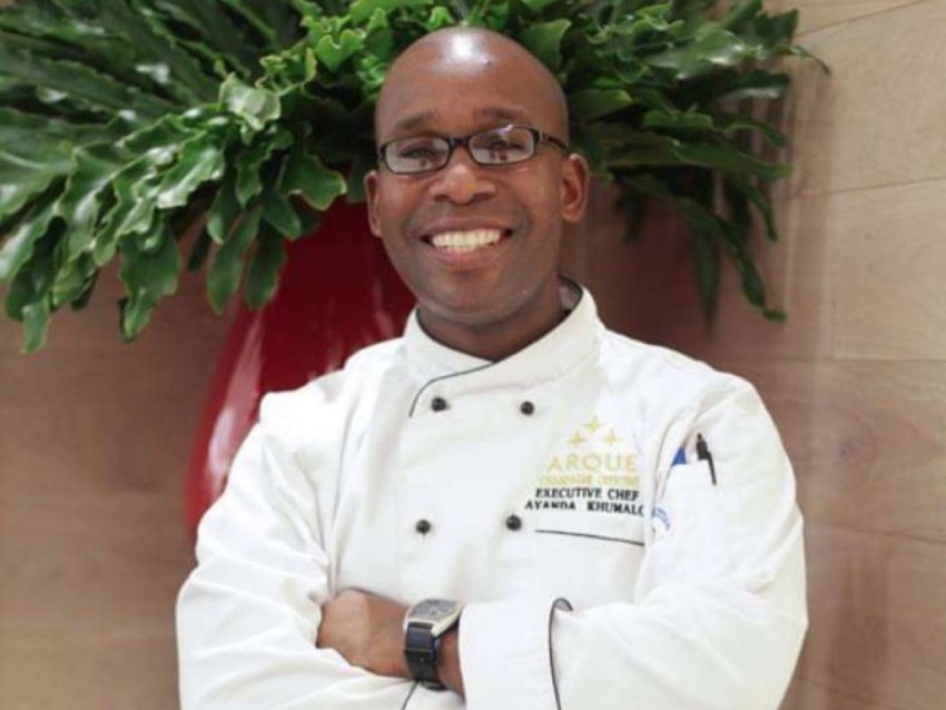 Executive Chef in uniform with arms crossed, smiling.