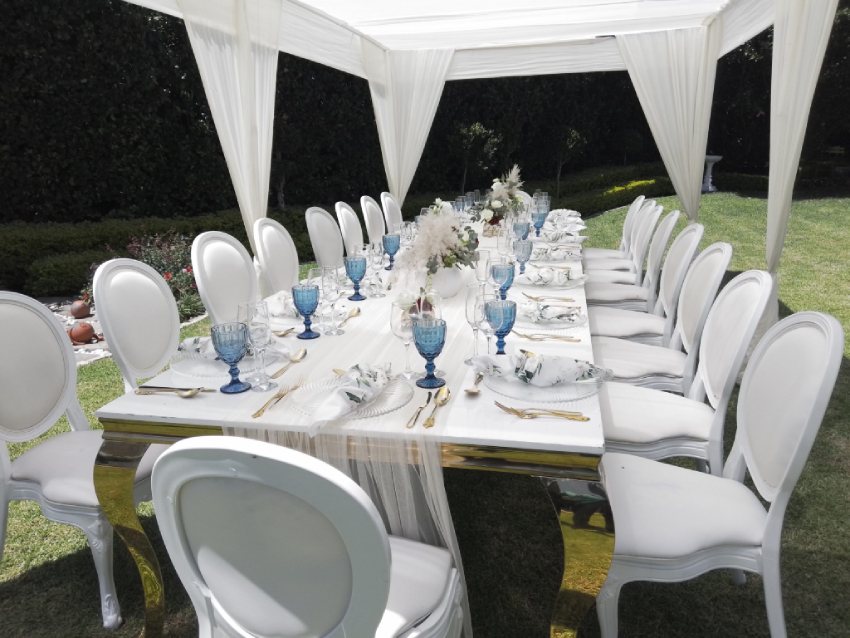 Outdoor dining setup with white chairs and blue glassware